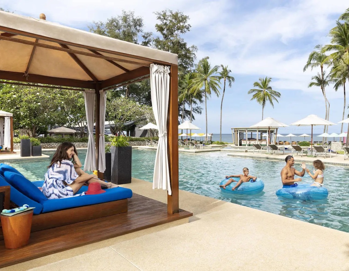 a family play and relax by the pool at a beachfront resort in phuket