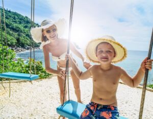 a mother pushes her son on a swing by the beach in Phuket