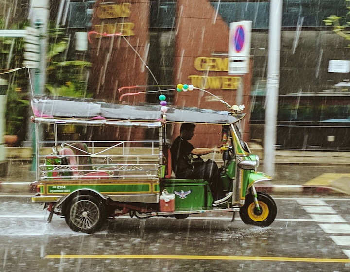 a tuk tuk drives through the rain in Phuket