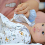 Newborn baby being dressed by his confinement nanny in hong kong, pui yuet services in HK