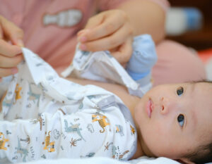Newborn baby being dressed by his confinement nanny in hong kong, pui yuet services in HK