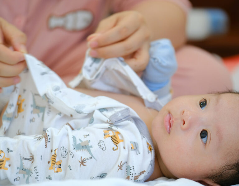 Newborn baby being dressed by his confinement nanny in hong kong, pui yuet services in HK
