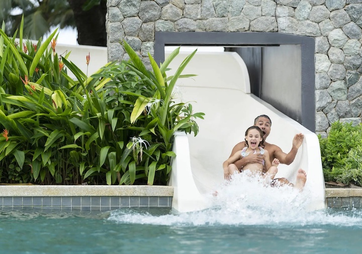 a father and child slide down the 55m waterslide at saii laguna beachfront resort phuket