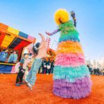 a little girl jumps to high five a performer in a rainbow costume at the Hong Kong aia carnival