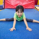 a Chinese girl doing a gymnastics pose at a preschool baby gym class in Hong Kong