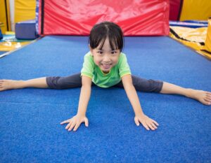 a Chinese girl doing a gymnastics pose at a preschool baby gym class in Hong Kong
