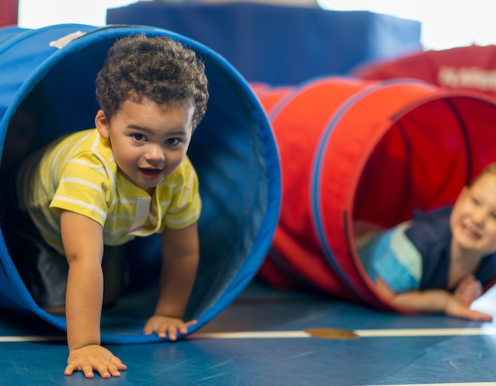 a toddler crawls through a tunnel at a baby gym class in Hong Kong