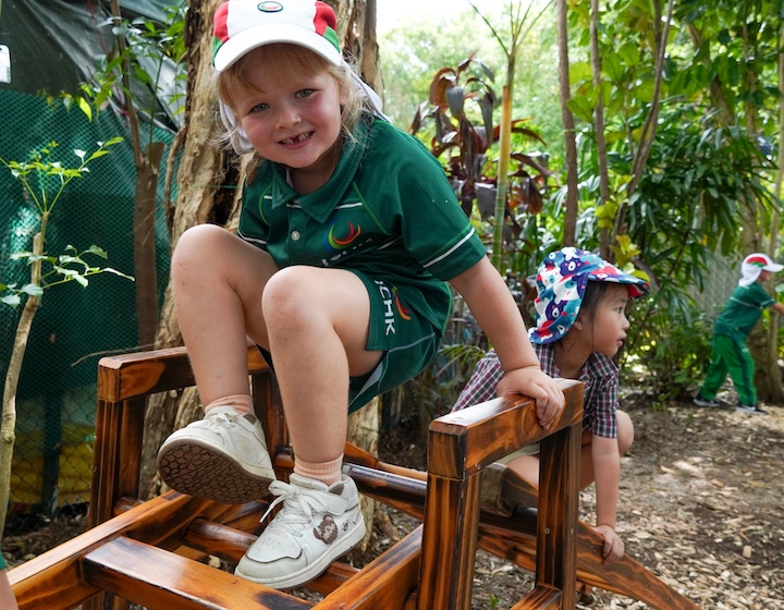 a happy girl plays on forest school equipment at ICHKHLY Kindergarten and Primary School