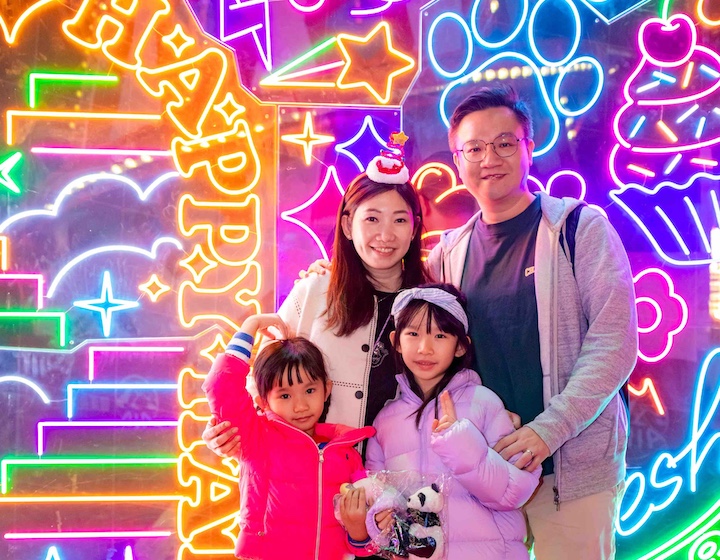 a Hong Kong family poses in front of the neon display at the winter carnival 2026-2027 on central harbourfront