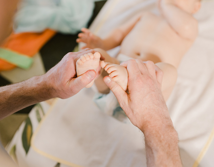 Parent holding baby's feet during an age appropriate stretch at Little's baby class in Hong Kong
