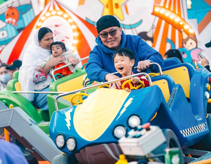 a father and his toddler son ride one of the rides for little kids at Hong Kong's AIA Carnival