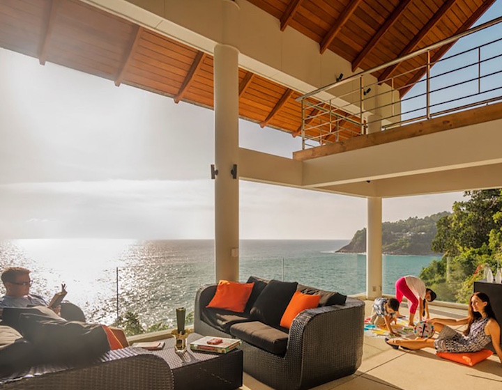a family relaxes and plays games on the balcony over looking the ocean at phuket villa Baan Pat Talee Estate in Kamala