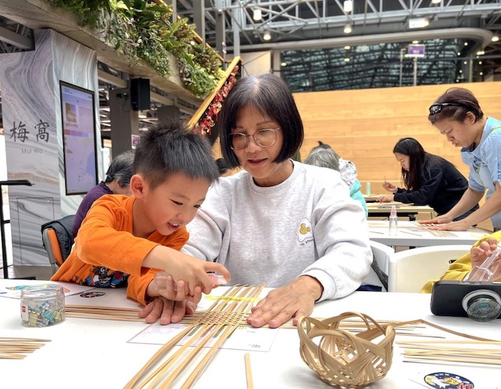 a grandmother helps a boy weave a basket as part of the cultural celebrations at Ping Shan Living Theatre