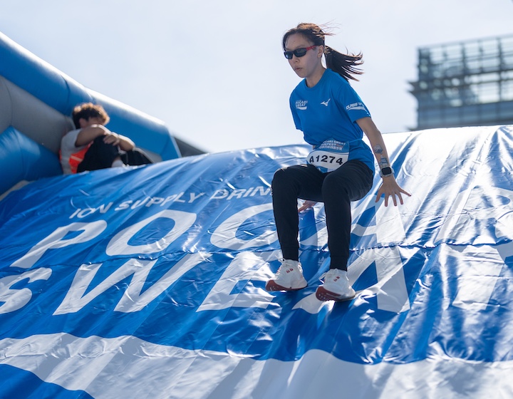 a woman slides down an inflatable obstacle at the Picard Sweat fun run in Hong Kong