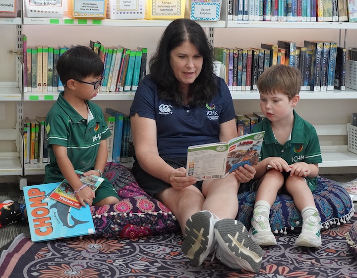 a teacher reads to two kindergarten students in the library at ICHKHLY Kindergarten and Primary