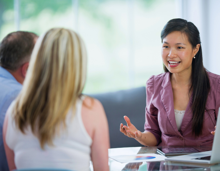 female financial planner speaking to a couple about their finances in an office