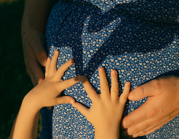 little kids hands on a pregnant woman's stomach making a heart, family photo taken by Nestology Studio in Hong Kong