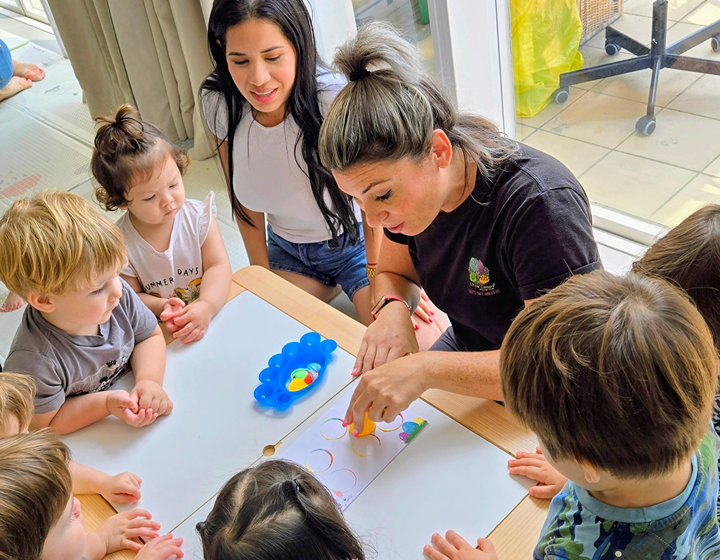 Teacher, toddlers and caregivers around a table in a Little Leaps playgroup in Hong Kong, Tung Chung/Discovery Bay