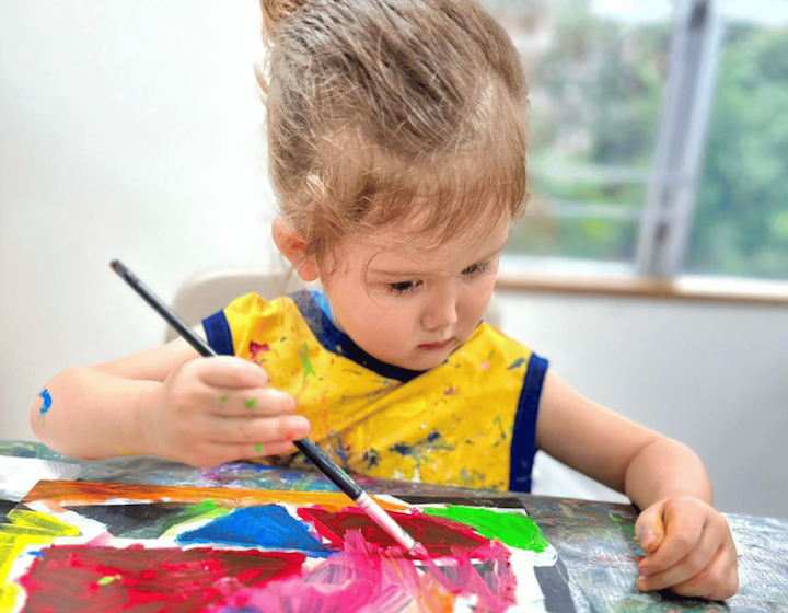 a young girl learns to paint at an after school art class in Hong Kong