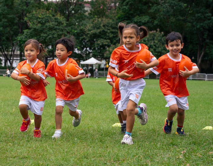 girls and boys running with a football at a Minisport after-school sports class in Hong Kong